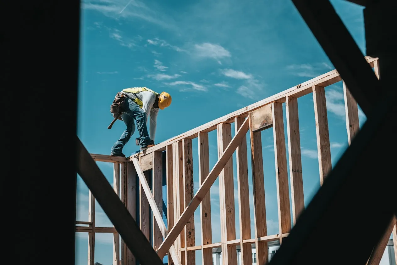 Wooden Scaffold of a building undergoing a construction, with a man in safety equipment on top